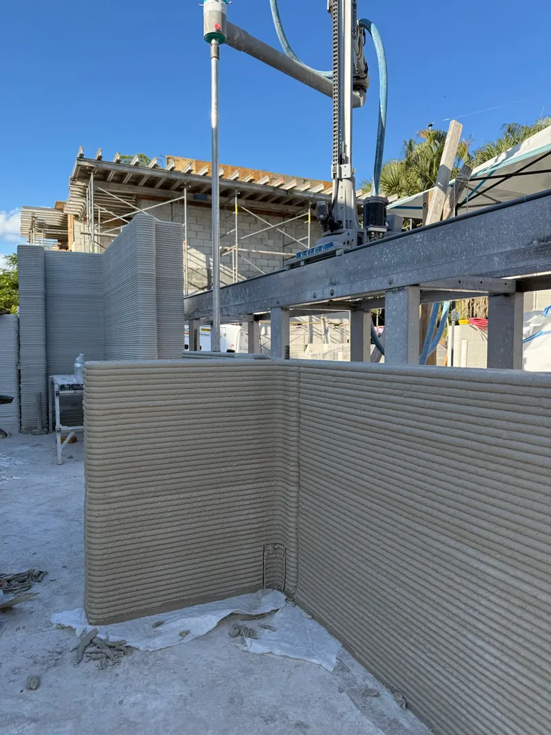 The robotic arm extruding a concrete wall on site.